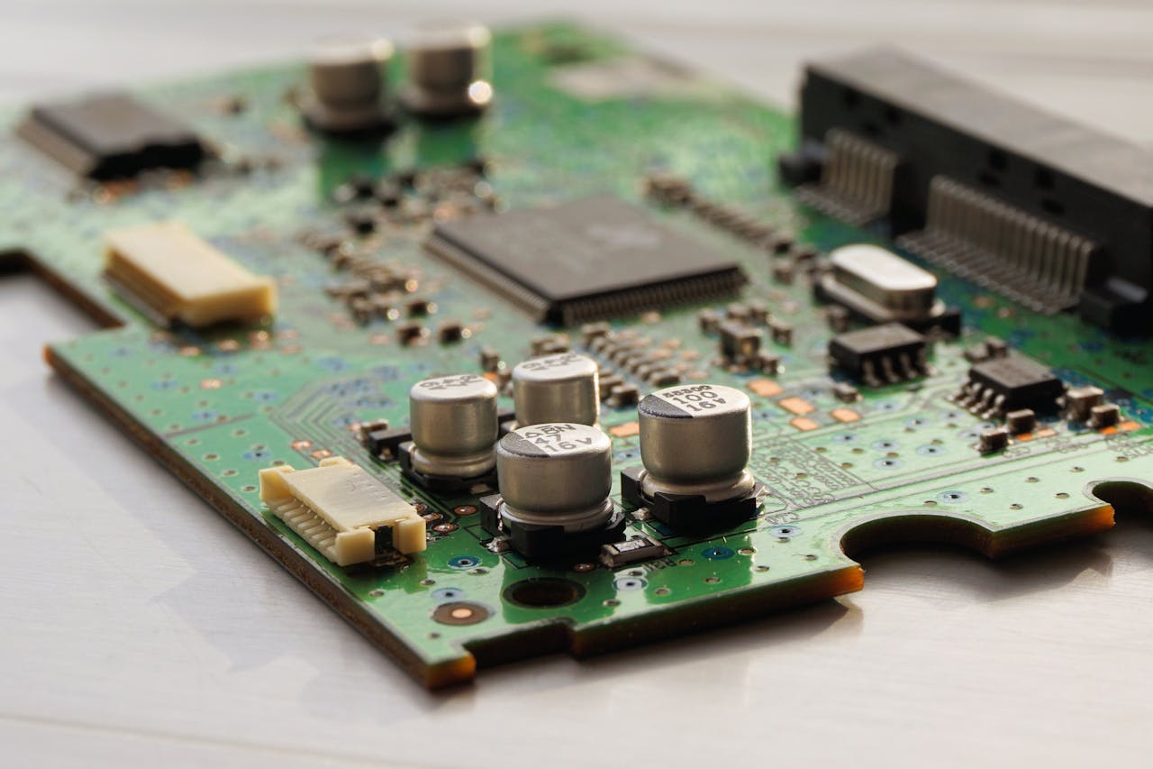 hero-img-02 Detailed view of a green circuit board featuring capacitors and microchips.