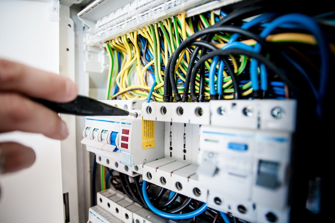 gallery-2 Hand of electrician working on a circuit breaker panel with colorful wires, ensuring safe electrical connections.