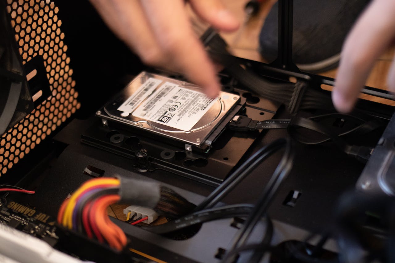 hero-img-01 Hands installing a hard drive in a computer case, emphasizing technology and connectivity.