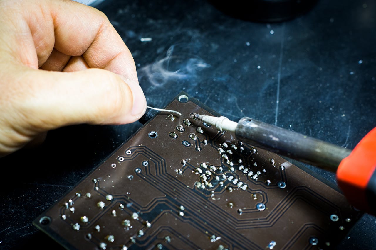 our-services-3 Hand soldering on a printed circuit board, showcasing electronic craftsmanship.